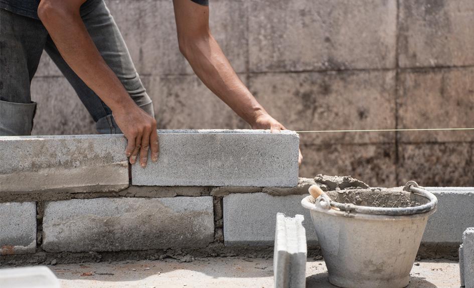 A construction worker builds a wall with concrete and mortar